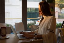 Femme utilisant un ordinateur portable dans le café — Photo de stock