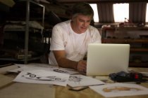 Meccanico maschio utilizzando laptop in garage — Foto stock