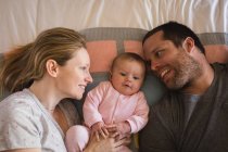 Parents lying with baby on bed in bedroom at home — Stock Photo