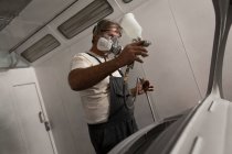 Meccanico maschio utilizzando vernice spray in garage — Foto stock
