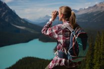 Female hiker looking through binoculars at countryside on a sunny day — Stock Photo