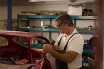 Homme mécanicien écriture sur presse-papiers dans le garage — Photo de stock