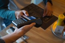 Close-up of man paying with NFC technology on credit card in cafe — Stock Photo