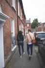 Вид сзади на пару, идущую по тротуару в городе — стоковое фото