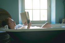 Жінка читає книгу у ванній кімнаті — стокове фото