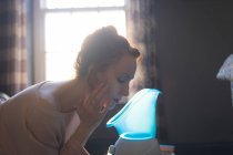 Donna che utilizza vaporizzatore facciale a casa — Foto stock