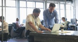 Бізнес-колеги обговорюють ноутбук в офісі — стокове фото