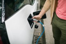 Close-up of man charging electric car at charging station — Stock Photo