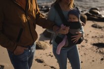 Partie médiane des parents avec bébé marchant sur la plage — Photo de stock