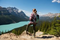 Wanderin steht an einem sonnigen Tag mit Rucksack auf dem Land — Stockfoto