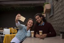 Happy couple taking selfie at outdoor cafe — Stock Photo