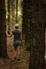 Rückansicht einer Frau, die im Wald steht — Stockfoto