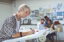 Female executive working on drafting table in office — Stock Photo