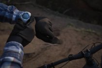 Mann mit Fahrrad nutzt Smartwatch auf dem Land — Stockfoto