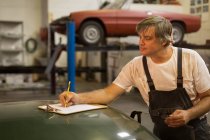 Masculino mecânica escrita na área de transferência na garagem — Fotografia de Stock