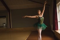Belle ballerine pratique la position de ballet arabesque en studio de danse — Photo de stock