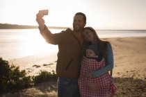 Genitori felici con bambino scattare selfie sulla spiaggia — Foto stock