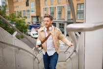 Smart man walking up stairs in city — Stock Photo