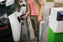 Man charging electric car at charging station — Stock Photo