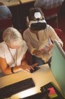 Visão de alto ângulo de executivas usando headset realidade virtual e tablet digital na mesa no escritório — Fotografia de Stock