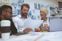 Executives discussing over blueprint at desk in office — Stock Photo