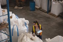 Женщина-работница с цифровым планшетом, проверяющая зерно на складе — стоковое фото