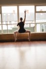 Балерина растягивается на барре во время занятий балетным танцем в танцевальной студии — стоковое фото