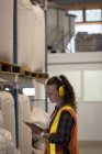Travailleur féminin utilisant une tablette numérique dans un entrepôt — Photo de stock