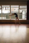 Bailarina practicando danza de ballet cerca de ventana en estudio de danza - foto de stock