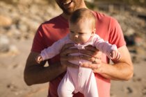 Primer plano del padre sosteniendo al bebé en la playa - foto de stock