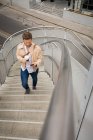 Kluger Mann geht Treppe hinauf, während er Handy benutzt — Stockfoto