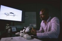 Homme cadre examinant un modèle de voiture dans le bureau — Photo de stock