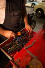 Mecánico masculino quitando herramientas del cajón en el garaje - foto de stock