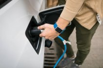 Gros plan de l'homme rechargeant une voiture électrique à la station de recharge — Photo de stock