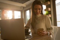 Junge Frau benutzt Handy in Café — Stockfoto