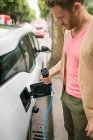 Smart man checking plug of charger at charging station — Stock Photo