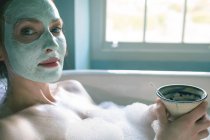 Frau mit Kaffeetasse in Badewanne im Bad — Stockfoto