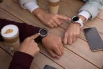 Gros plan du couple utilisant smartwatch au café extérieur — Photo de stock