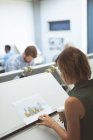 Female executive looking at blueprint on drafting table in office — Stock Photo