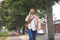 Умный человек разговаривает по мобильному телефону во время прогулки по улице — стоковое фото