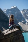 Giovane donna seduta su una roccia vicino al fiume — Foto stock