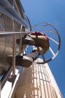 Blick in den niedrigen Winkel: Arbeiterin klettert auf Biogasanlage — Stockfoto