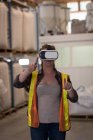 Trabajadora con auriculares de realidad virtual en almacén - foto de stock