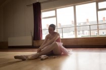 Красива балерина зав'язує взуття мереживом в танцювальній студії — стокове фото