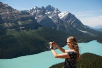 Жінка клацає фотографії з мобільним телефоном в сонячний день — стокове фото