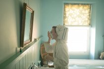 Mulher aplicando máscara facial no banheiro em casa — Fotografia de Stock