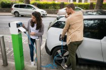 Couple recharge voiture électrique à la station de recharge — Photo de stock