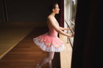 Продумана балерина дивиться крізь вікно в танцювальній студії — стокове фото