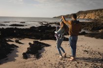 Coppia che balla sulla spiaggia con il proprio bambino in una giornata di sole — Foto stock