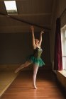 Belle ballerine pratique la position de ballet arabesque en studio de danse — Photo de stock
